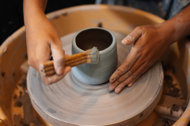 Close up on skillful hands making and sculpting pottery jar on potter wheel with tools and water in workshop, Creative and artwork, Handmade craft