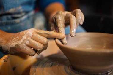 Becerikli ellerle çömlek kavanozunu çömlekçi çarkında yapmak ve yontmak üzerine atölyede aletler ve su, yaratıcı ve sanat eserleri, el yapımı el işi.