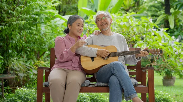 stock image Senior couple portrait, Happy senior grandparents playing guitar and singing songs having fun together happily at home, Healthy senior retired people enjoying with music in the garden