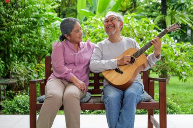 Yaşlı çift portresi, gitar çalan ve şarkı söyleyen mutlu yaşlı büyükanne ve büyükbaba evde mutlu mesut eğlenen sağlıklı yaşlı emekli insanlar bahçede müzikle eğleniyor.