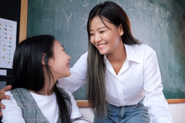 Sınıftaki neşeli liseli kız, okulda öğretmenle ders çalışan mutlu öğrenci, gelişme öğrenme, okula dönüş konsepti.