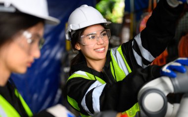 Professional maintenance worker working with machine robotic arms at industrial factory, Technician engineer checking safety of machine and maintenance robotic arms