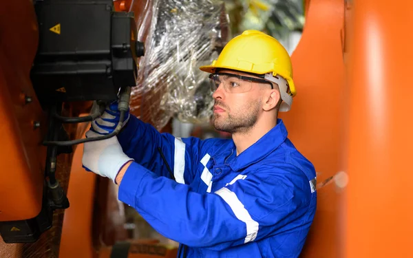 Professional maintenance worker working with machine robotic arms at industrial factory, Technician engineer checking safety of machine and maintenance robotic arms