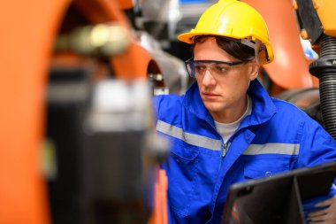 Professional maintenance worker working with machine robotic arms at industrial factory, Technician engineer checking safety of machine and maintenance robotic arms