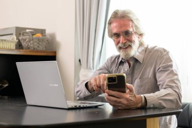 Senior grandfather using laptop and smart phone at home, Happy retirement people relaxing and resting at home, Healthy and happy senior people concept