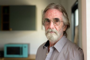 Portrait of healthy senior man with red cup of tea, Retirement man resting and relaxing at home