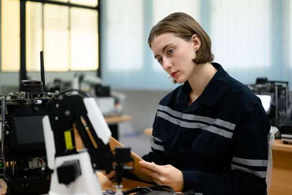 stock image Female technician engineer using laptop checking and operating automatic robotic machine at industrial factory, Worker working with robotic system in factory