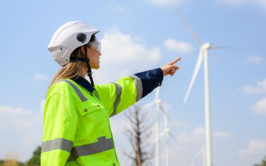 Rüzgar türbini alanında çalışan mutlu kadın mühendis, temiz enerji kaynaklarını araştıran ve geliştiren çevre mühendisi, Yeşil ekolojik enerji üretimi, Rüzgar