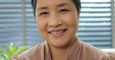 Gülümseyen son sınıf kadın portresi, çekici gülüşü olan, kameraya bakan, özçekim yapan ve evde video hikayeleri kaydeden sağlıklı yaşlı kadın.