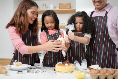 Evde aktiviteleri olan aile, ailesiyle pasta yapan çocuk, mutfakta birlikte eğlenen aile, mutfak aktiviteleri konsepti.