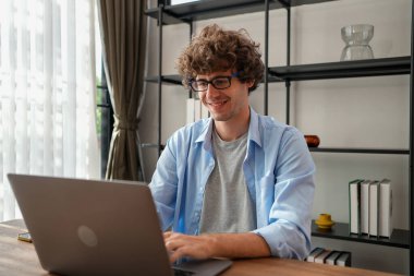 Evde çalışan dizüstü bilgisayar kullanan, bilgisayarını kullanan, bilgisayarını kullanan, evde e-posta gönderen, bilgisayarını kağıt ve belgelerle dolduran bir adam.