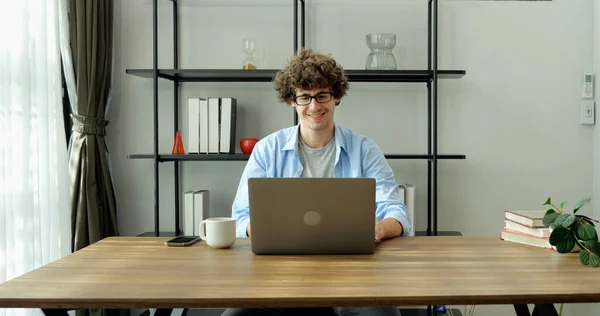 Smiling man with eyeglasses using laptop working at home, Happy businessman using laptop sending email working at home, Freelancer typing on computer laptop with paperworks and documents