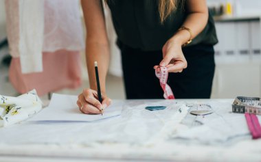 Atölyede çalışan güzel kadın terzi, kadın terzi ölçü ve kıyafet provaları, manken giyimi atölyesinde terzilik, küçük işletme sahibi.