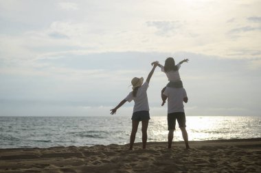 Mutlu Asyalı aile tatilde sahilde birlikte seyahat eder. Sahil yolculuğu yapan bir aile. İnsanlar tatilden zevk alıyor. Yüksek kalite fotoğraf