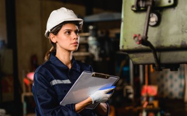 Confident female technician engineer worker checking and inspecting machine at manufacturing factory, Machinery maintenance concept