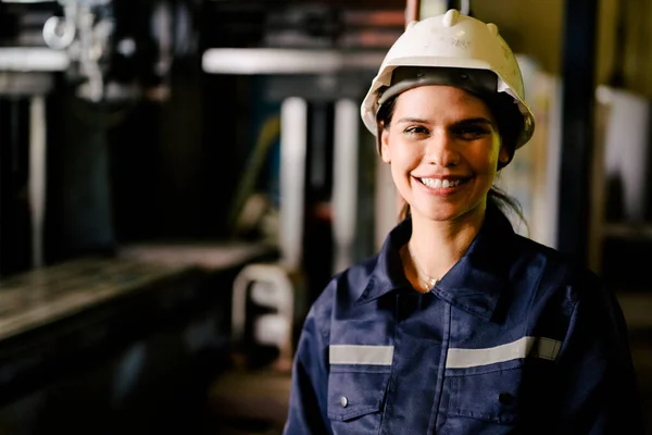 Portrait of happy female industrial worker in white hard hat smiling working at manufacturing plant, Industrial engineer portrait