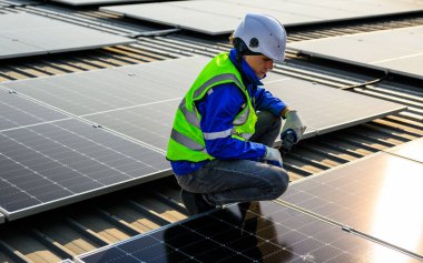 Güvenlik kask kontrol sistemine sahip profesyonel mühendis üniformalı işçi ve güneş çiftliğine fotovoltaik paneller monte eden baret.