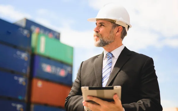Smart businessman checking and working at overseas shipping container yard, Logistics supply chain management, International good import and export