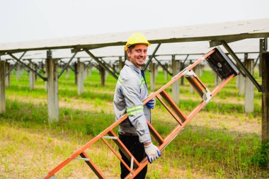 Güneş pili çiftliğinde güneş panellerini kontrol eden ve koruyan profesyonel mühendis, ekolojik güneş çiftliğinde çalışan teknisyen, temiz enerji teknolojisi olan insanlar, yenilenebilir enerji, güneş enerjisi santrali