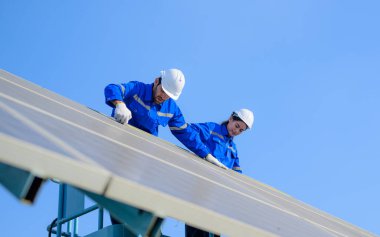 Endüstriyel güneş pili çiftliğine güneş panelleri kuran teknisyen ekibi, elektrik santralinde çalışan mühendisler, güneş panelleri alanında elektrik sistemi bakımı, çevre dostu ve temiz enerji
