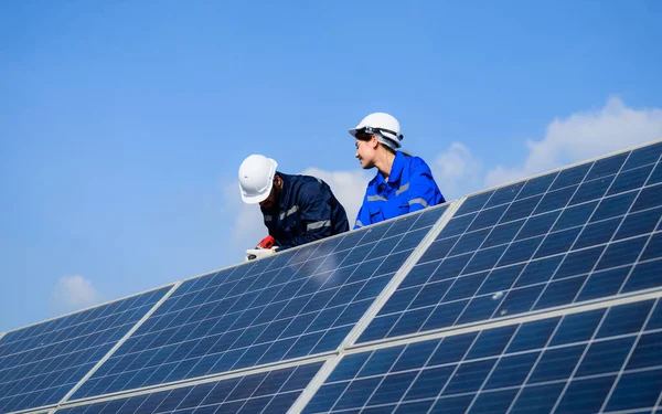 Endüstriyel güneş pili çiftliğine güneş panelleri kuran teknisyen ekibi, elektrik santralinde çalışan mühendisler, güneş panelleri alanında elektrik sistemi bakımı, çevre dostu ve temiz enerji