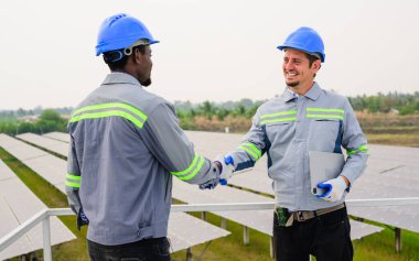 Güneş pili çiftliğindeki güneş panelleri sistemini kontrol eden ve koruyan mutlu bakım mühendisi, ekolojik güneş çiftliğinde çalışan teknisyen, temiz enerji teknolojisi olan insanlar, yenilenebilir enerji, güneş enerjisi,