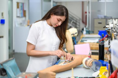 Protez bacağı olan genç bir protez teknisyen laboratuarda çalışıyor ve kalitesini kontrol ediyor. Protez üretiminde yüksek teknoloji mühendisi.