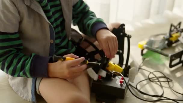 Stemでロボットカーと電子ボードをコーディングすることを学ぶ幸せな男の子 ロボット車を作る小さな男の子 Stemコーディング工学を持つ子供 子供の技術学習 — ストック動画