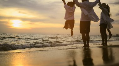 Mutlu bir aile babası, anne kız ve oğlu sahilde birlikte tatil yapıyor, plajda seyahat eden bir aile, tatilde sahilde birlikte seyahat eden mutlu bir Asyalı aile, sahil seyahati yapan bir aile,