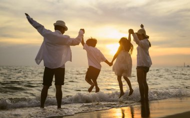 Mutlu bir aile babası, anne kız ve oğlu sahilde birlikte tatil yapıyor, plajda seyahat eden bir aile, tatilde sahilde birlikte seyahat eden mutlu bir Asyalı aile, sahil seyahati yapan bir aile,
