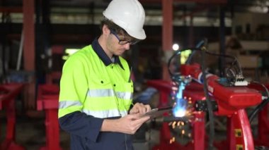 Tamir atölyesinde tablet kullanan makine bakım mühendisi, imalat fabrikasında, otomobil fabrikasında makineyi kontrol eden ve denetleyen tamirci.