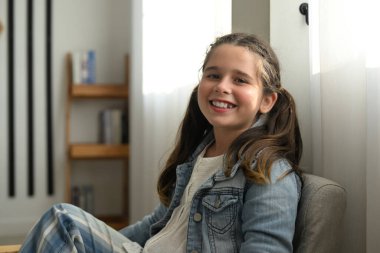 Kameraya gülümseyerek bakan mutlu bir ortaokul öğrencisi kameraya poz veren bir kız, sınıfta ders alan çocuklar, okula geri dönen eğitimli çocuklar,