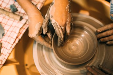 Erkek çömlekçinin kadın öğrencilere çanak çömlek üzerinde seramik çömlek yapmayı öğrettiği, profesyonel bir zanaatkar çömlekçinin atölyede çömlekçi çemberinde kilden sürahi yaptığı, geleneksel el işi.
