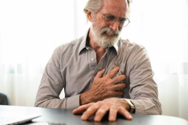 Senior man holding hand on chest and suffering from heart problem at home, Grandfather with heart attack suffer, People with health problems