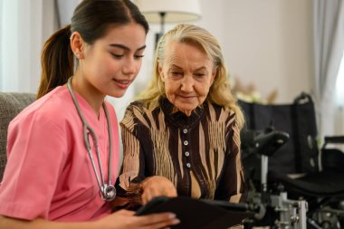 Ev ziyaretinde yaşlı bir hastayla konuşan kadın doktor, sağlık hizmetleri olan insanlar, evde ya da huzurevinde yaşlı bir hastayla ilgilenen doktor ya da hemşire, stetoskobu olan profesyonel kadın doktor.