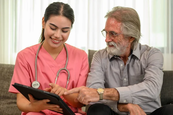 Happy female doctor with stethoscope visiting patient, Doctor or nurse caregiver with senior patient at home or nursing home, Doctor and senior man during home visit