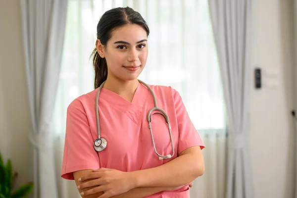 Smiling portrait of professional female doctor with stethoscope visiting patient, Doctor or nurse caregiver with senior patient at home or nursing home, Doctor and senior woman during home visit