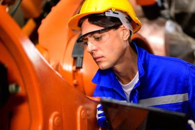 Sanayi fabrikasında makineli robotik silahlarla çalışan profesyonel mühendis, makine ve bakım robotik silahlarının güvenliğini kontrol eden teknisyen, mühendis kontrol edip kontrol ediyor.