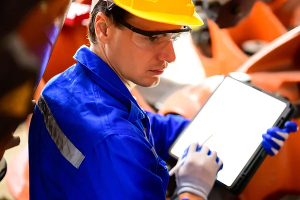 stock image Expertise technician using digital tablet working at industrial plant, Technician engineer checking safety of machine and maintenance robotic arms, Engineer checking and controlling machinery at