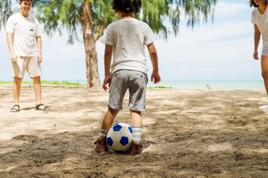 Mutlu Asyalı aile tatilleri, mutlu aile baba ve çocuklar birlikte futbol oynuyorlar, insanlar sahilde, tatilde ve seyahat konseptinde eğleniyor.