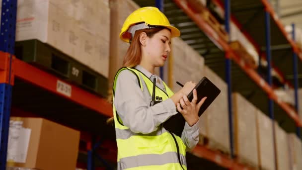 ヘルメットの倉庫管理者は 倉庫内の商品の背景を持つ棚の商品や供給をチェックするためにタブレットを使用して 物流やビジネスの輸出 工業工場の作業コンセプト — ストック動画