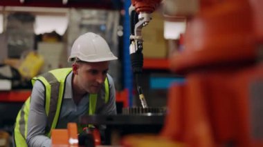 Endüstriyel imalat fabrikasında çalışan güvenlik üniforması koruması olan endüstri mühendisi depoda robot makinelerini kontrol eden ve kontrol eden teknisyen, mühendislik konsepti.