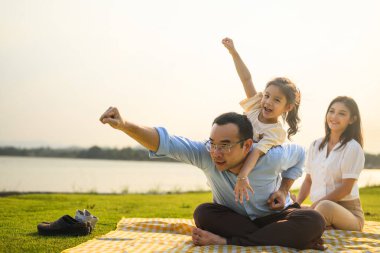 Mutlu bir aile hafta sonu parkta dinleniyor ve dinleniyor, aile babası ve kızı parkta piknik yapıyor, ebeveynler kızlarıyla seyahat ediyor, aile hayatı sürüyor. 