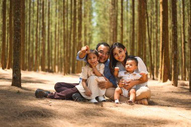 Mutlu ebeveynler ve çocuklar parkta gülümseyerek kameraya bakıyor, neşeli aile babaları ve çocukları parkta pikniğin tadını çıkarıyorlar, aileler kızlarıyla ve oğullarıyla birlikte doğada seyahat ediyorlar, aile yaşam tarzları. 