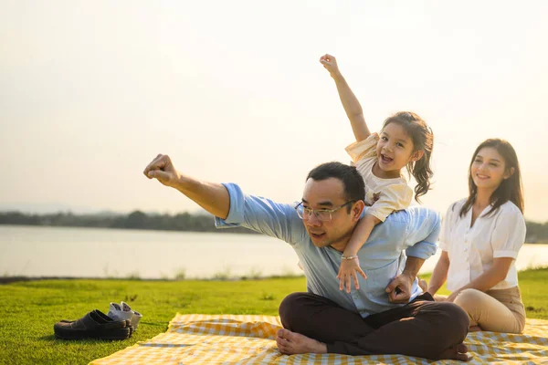 Happy family relaxing and resting in park together on weekend, Family father mother and daughter enjoying picnic at park, Parents travel with daughter, Family lifestyle