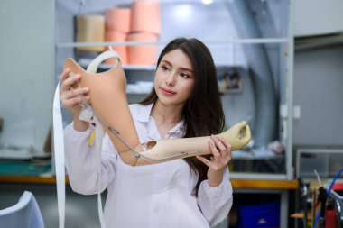 Protez kol kontrolü ve kontrol kalitesini elinde tutan genç protez teknisyen, laboratuarda çalışıyor, protez imalatında yüksek teknoloji uzmanı, yeni yapay