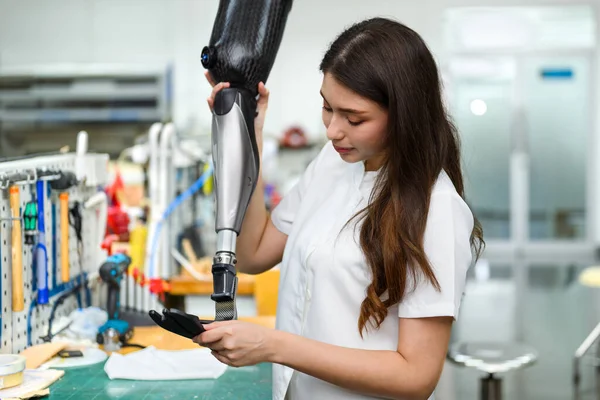 stock image Female technician assembling and fixing parts of modern prosthetic leg, Young prosthetic technician holding prosthetic leg checking and controlling quality working in laboratory, New artificial limb