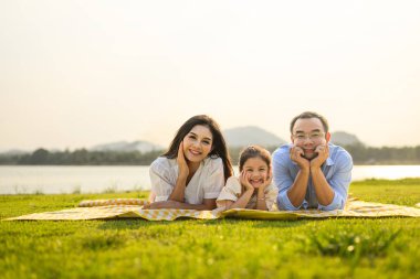 Mutlu bir aile hafta sonu parkta dinleniyor ve dinleniyor, aile babası ve kızı parkta piknik yapıyor, ebeveynler kızlarıyla seyahat ediyor, aile hayatı sürüyor. 
