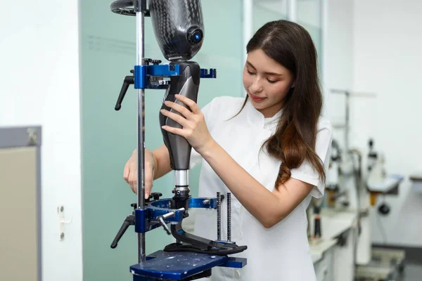 Stock image Female technician assembling and fixing parts of modern prosthetic leg, Young prosthetic technician holding prosthetic leg checking and controlling quality working in laboratory, New artificial limb