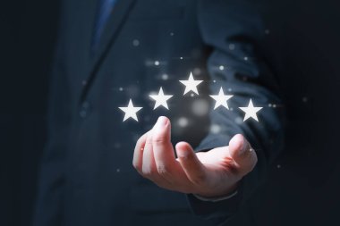 Sanal dokunmatik ekranda gülen surat ifadesine, Müşteri hizmetleri değerlendirmesine, Geri bildirim simgesine ve gözden geçirilecek en iyi puana basan iş adamı